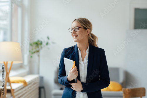 Smiling beautiful businesswoman holding tablet PC in office