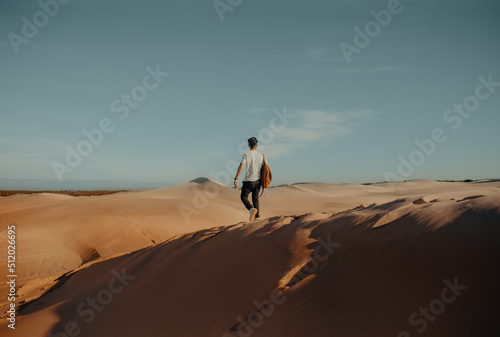 Young man walking in hot desert dunes in afternoon sun