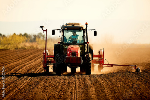 Farmer in tractor seeding soybean crops working at farm field photo