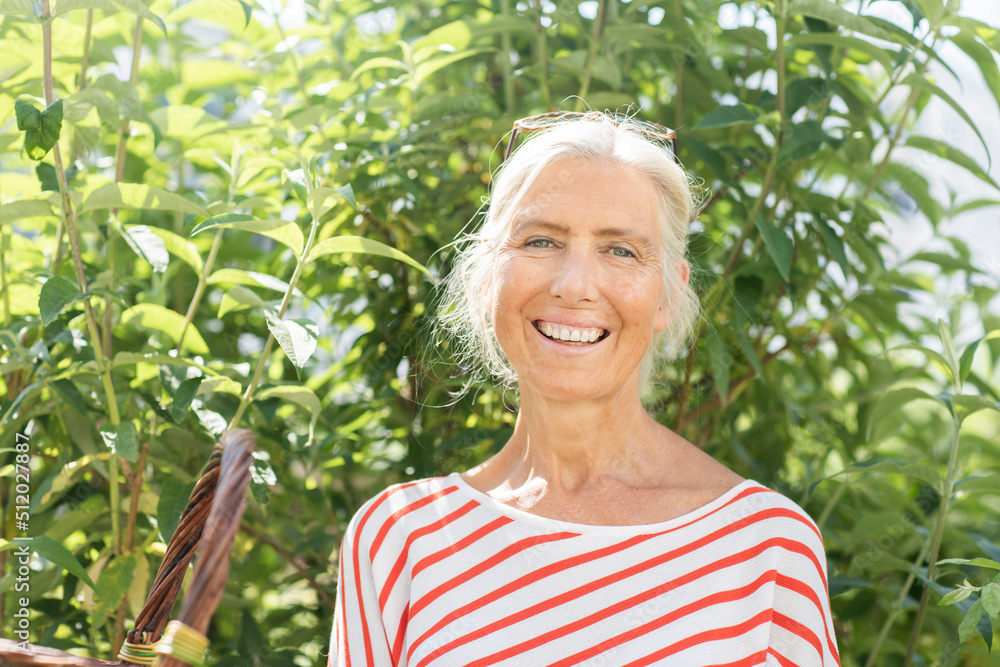 Happy mature woman in front of plants on sunny day Happy mature woman in front of plants on sunny day