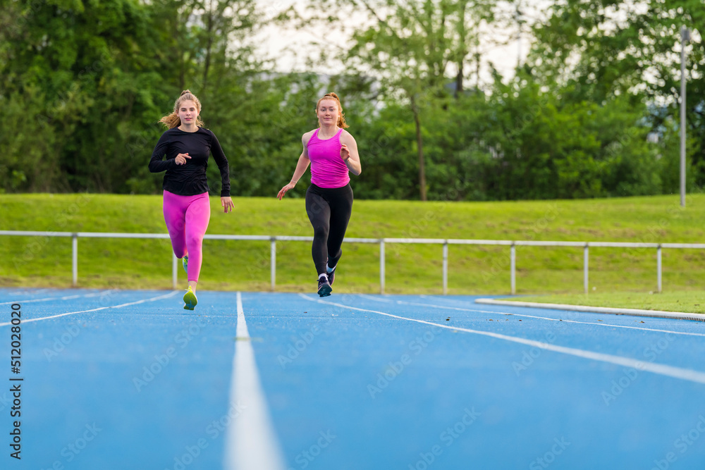 Young sportswomen running on sports track Young sportswomen running on sports track