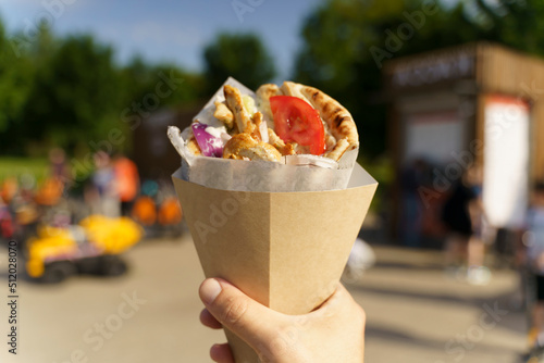 Fototapeta Naklejka Na Ścianę i Meble -  Greek street food gyros in hand. Greek and Mediterranean cuisine with meat in pita.