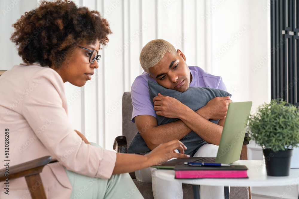 Young psychologist with patient discussing over laptop at office Young psychologist with patient discussing over laptop at office