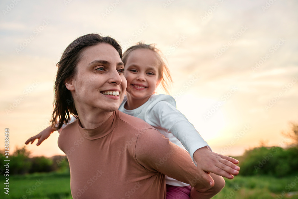 Smiling woman carrying girl piggyback in field Smiling woman carrying girl piggyback in field