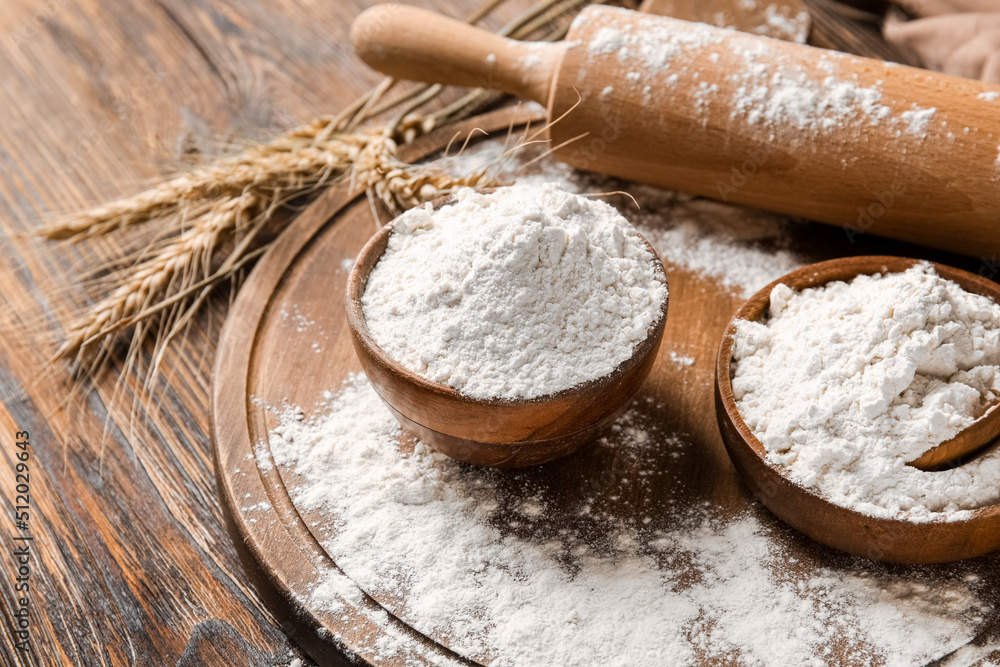Bowls with flour, rolling pin and wheat ears on wooden background Bowls with flour, rolling pin and wheat ears on wooden background