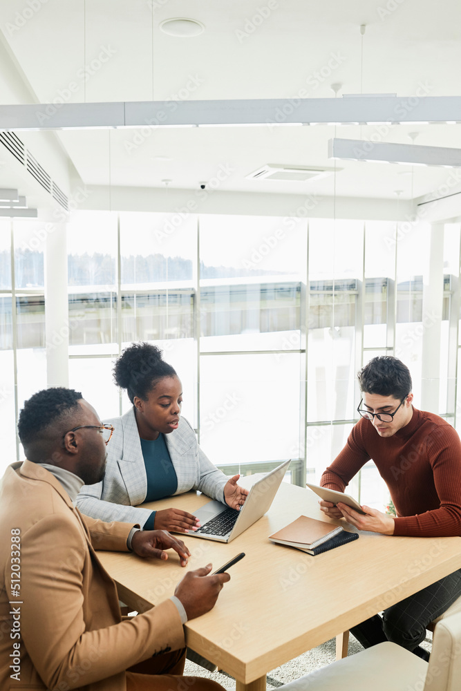 Young businesswoman discussing over laptop with colleagues sitting at desk in office Young businesswoman discussing over laptop with colleagues sitting at desk in office