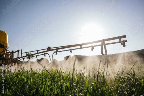 Crop sprayer spraying fertilizer on field on sunny day photo