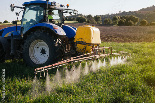 Farmer spraying fertilizer through sprayer sitting in tractor on field