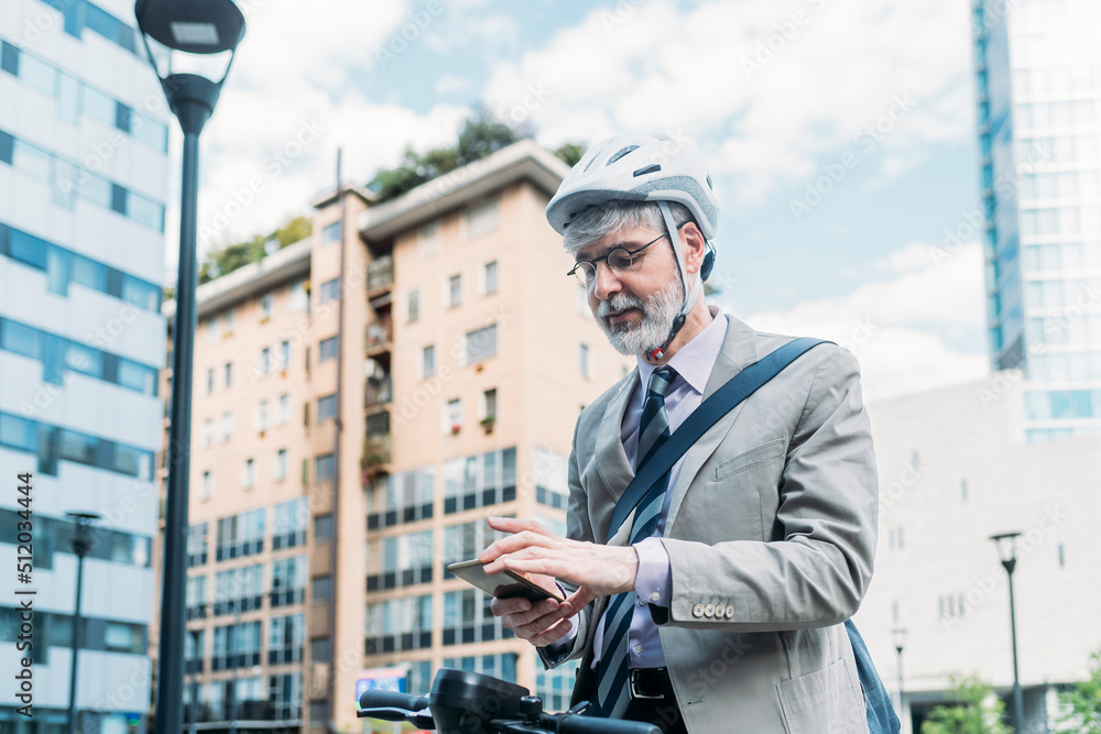 Businessman wearing cycling helmet using smart phone in front of buildings Businessman wearing cycling helmet using smart phone in front of buildings