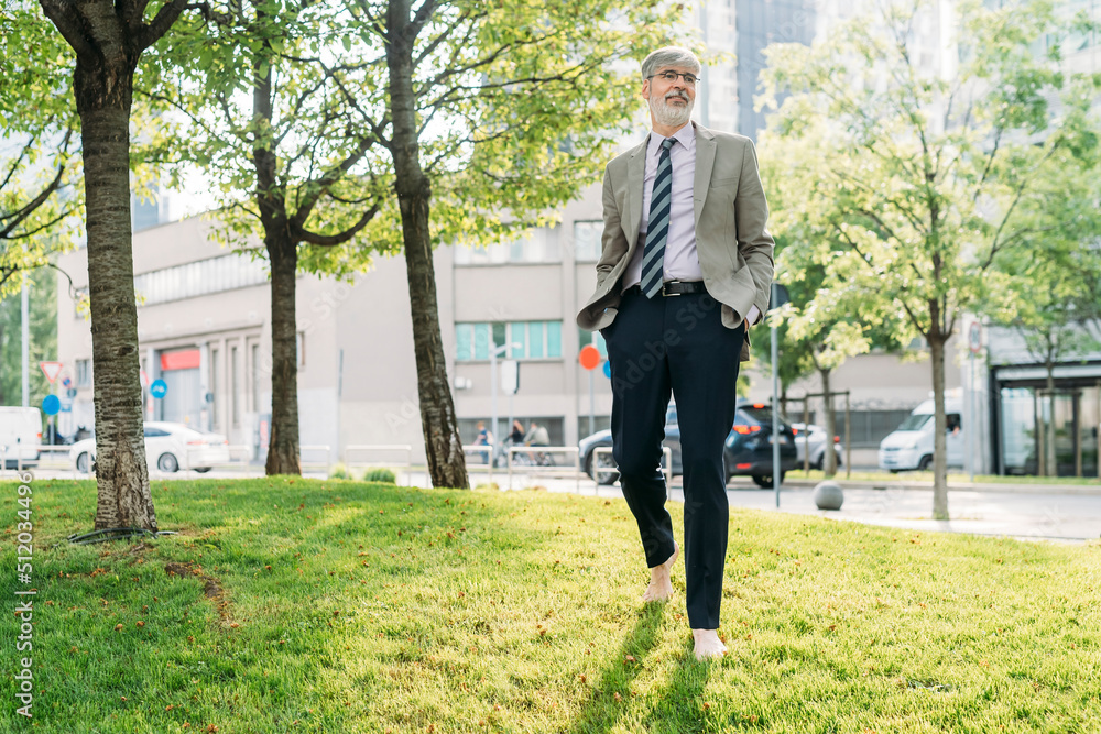 Smiling businessman with hands in pockets walking at park