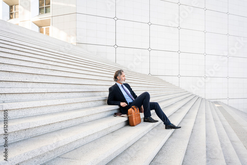 Mature businessman sitting with bag on steps photo
