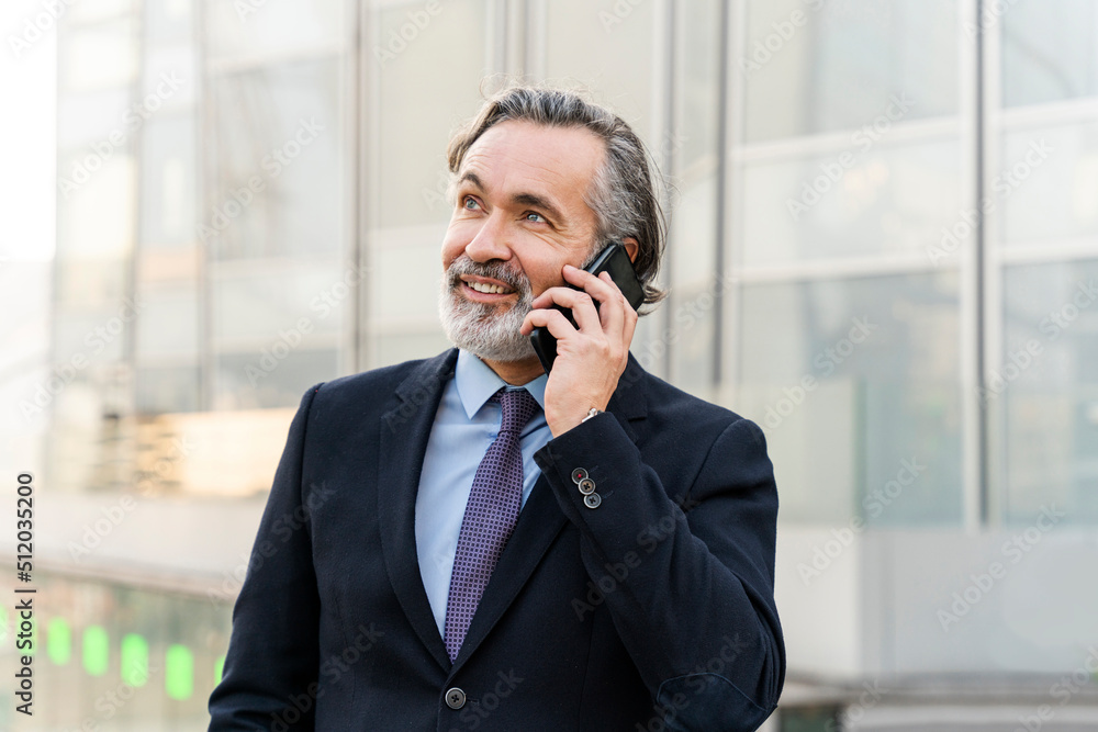 Smiling mature businessman with gray hair talking on smart phone Smiling mature businessman with gray hair talking on smart phone