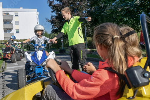 Young instructor assisting boy driving quadbike at traffic education training
