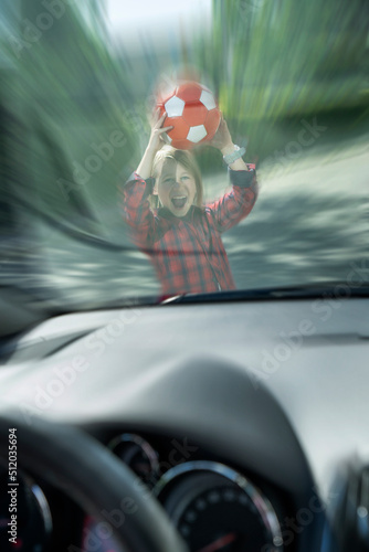 Scared boy with ball seen through windshield of car trying to prevent accident photo