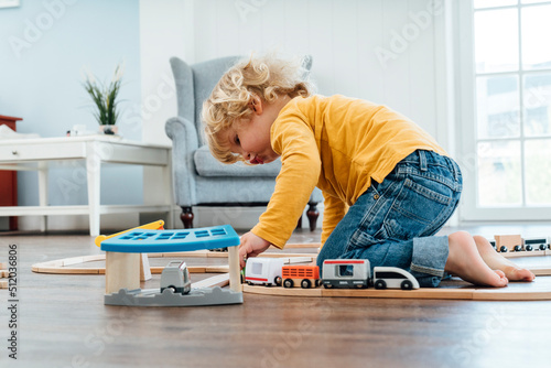 Blond boy playing with toy train set at home photo