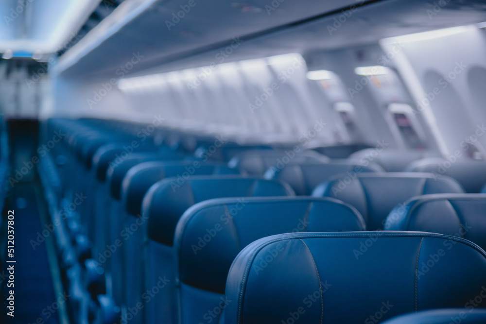 Fototapeta premium View of blurred empty passenger airplane seats in the cabin in blue colored, blurred of empty seat in the aircraft