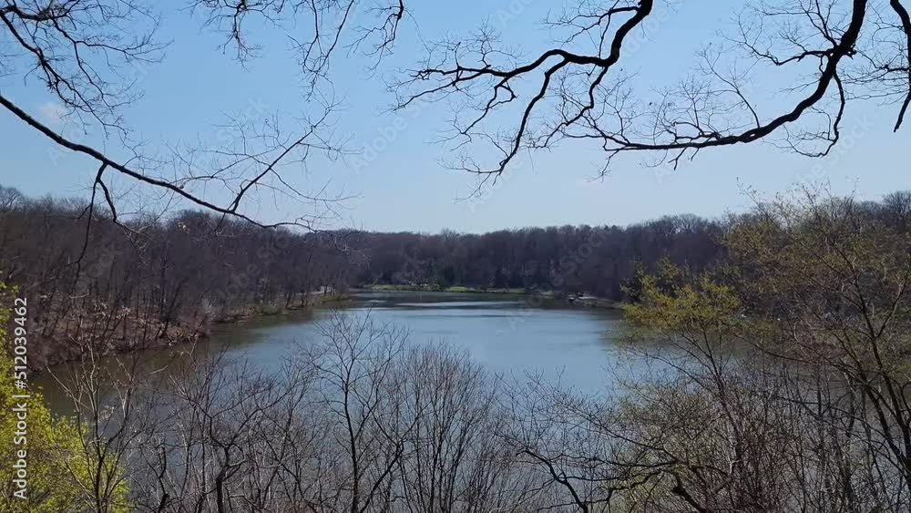 Large Lake in Early Spring with Most Trees Bare but Some Starting To Bud with Blue Skies and Sweeps Left to Right. Large Lake in Early Spring with Most Trees Bare but Some Starting To Bud with Blue Skies and Sweeps Left to Right.