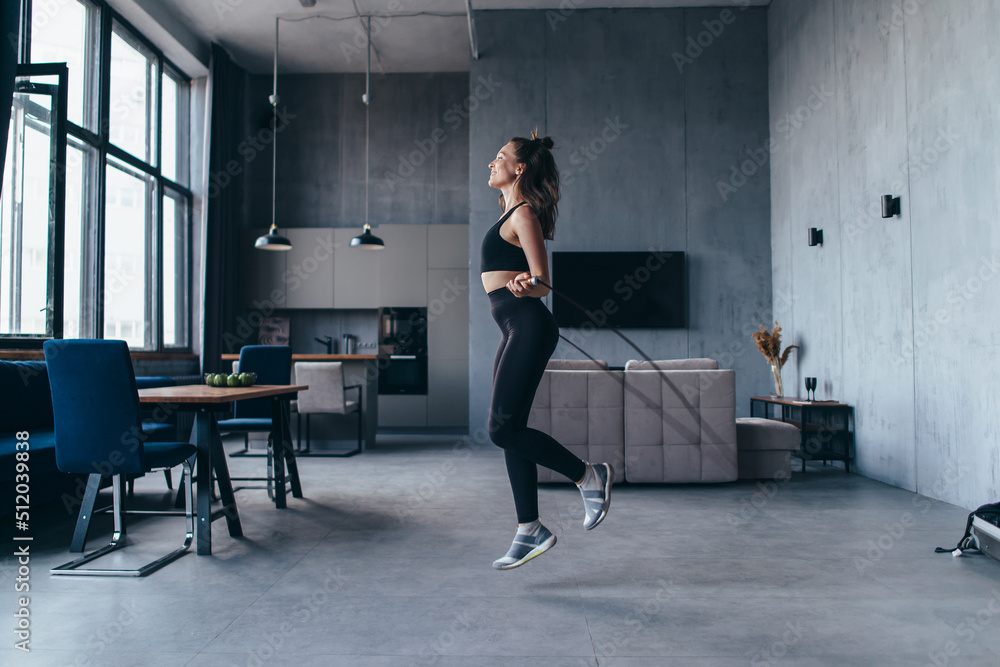 Fit woman with jump rope at home doing skipping workout. Fit woman with jump rope at home doing skipping workout.