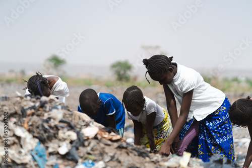 Four West African homeless children digging in a landfill looking after recyclable items to sell  poverty concept