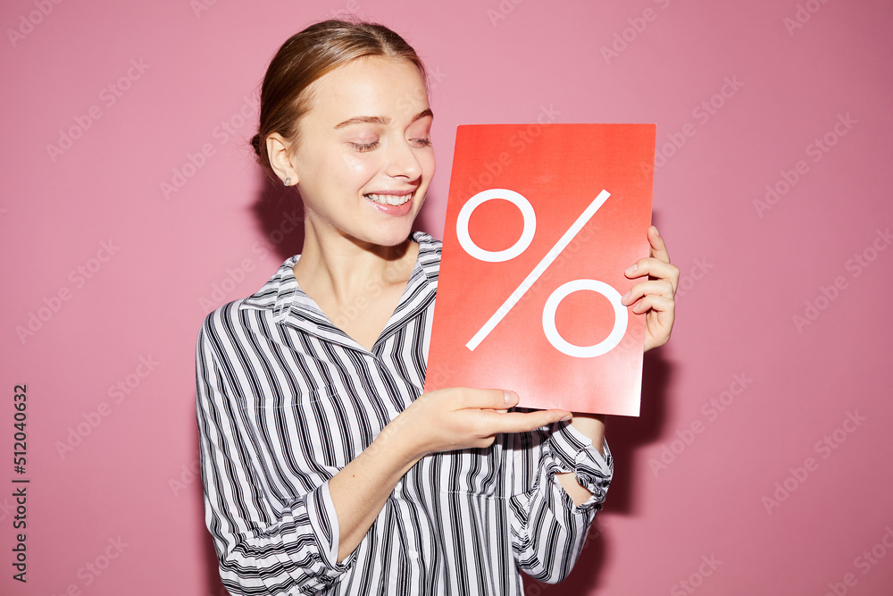 Positive attractive saleswoman holding percent banner while sharing information about special offer in shop Positive attractive saleswoman holding percent banner while sharing information about special offer in shop
