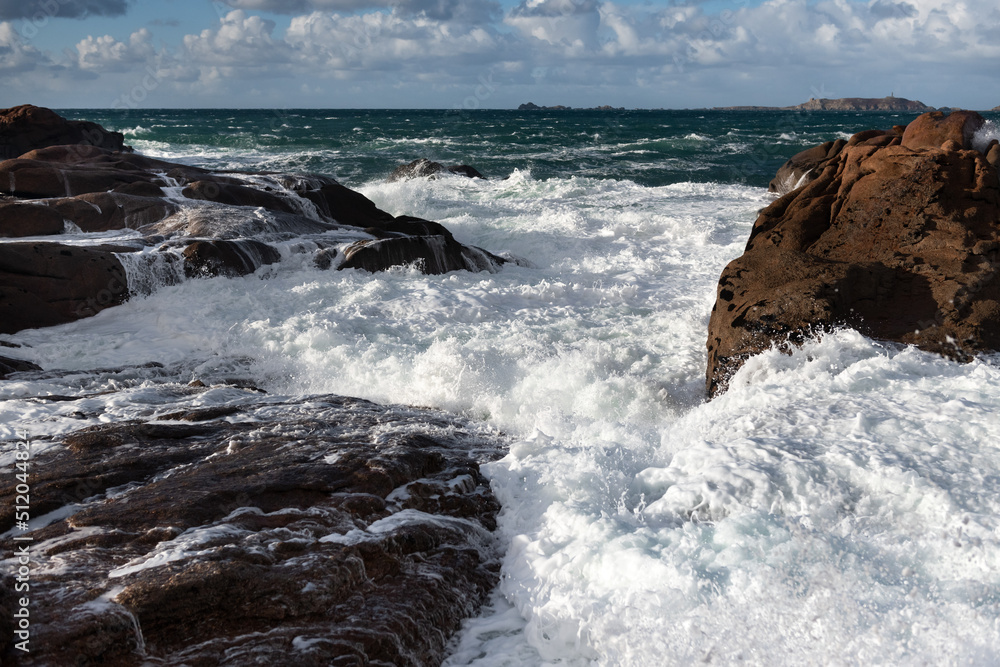Rough sea and big waves hit rocks creating enormous spray.