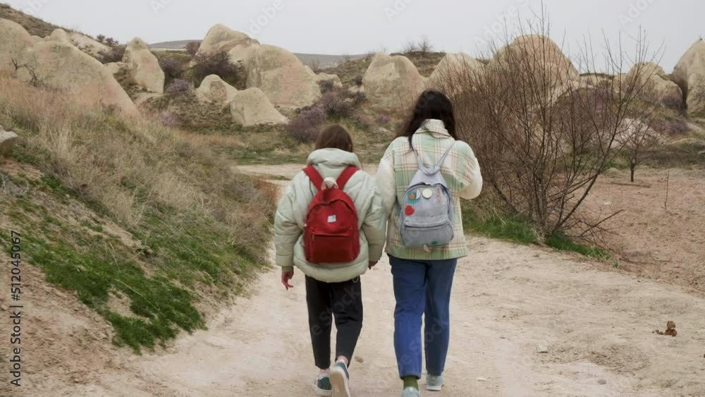 Back view of two unrecognisable women with backpacks walking through ...
