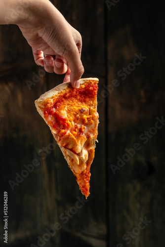Female hands holding Tasty hawaiian pizza with chicken and pineapple. food delivery, place for text, vertical image