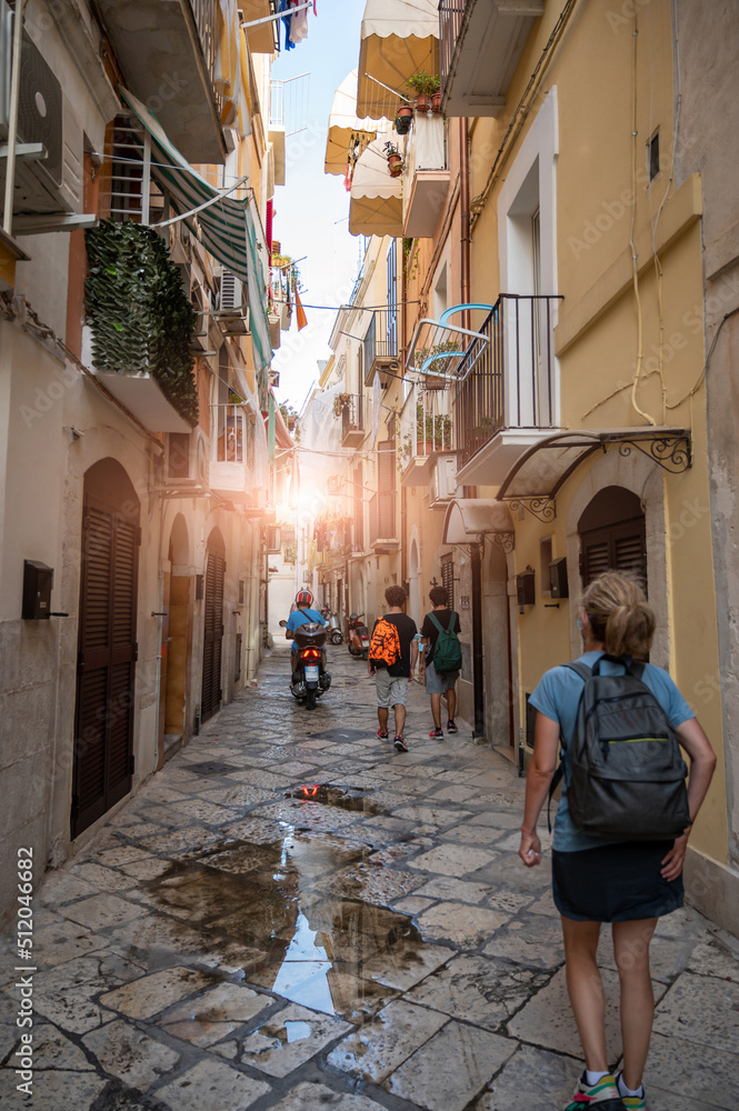 Bari, Puglia, Italy. August 2021. Tourists in the alleys of the historic center, the Bari Vecchia, full of charm and fascinating views. Paved street and out of the houses on the street.