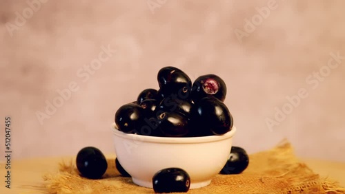 Rotating fresh jamun fruit on the dark background,turning indian blueberries on table,selective focus