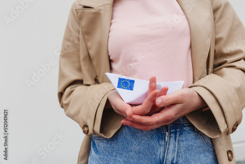 Woman holding paper boat with sticker of European Union Flag photo