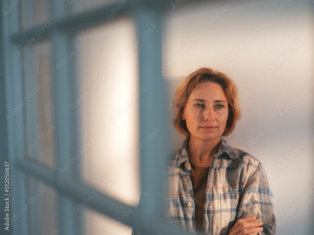 Mature woman with blond hair standing in front of wall Mature woman with blond hair standing in front of wall