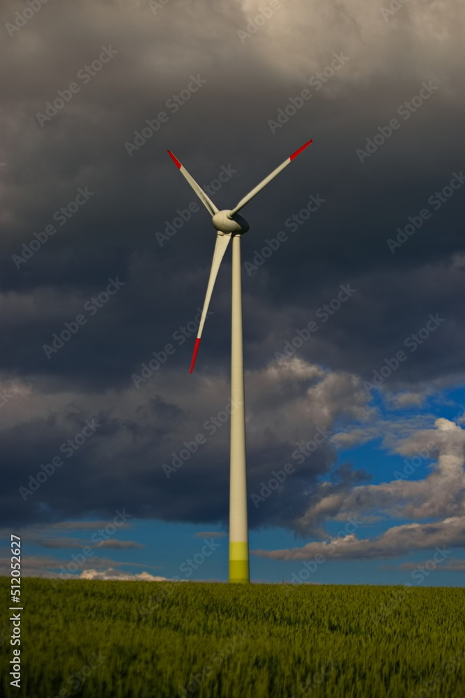 Fototapeta premium Windräder in der Landwirtschaft im Sommerwind dunkeler Himmel Wolken Energie von morgen im Getreidefeld Sturm am Windrad 