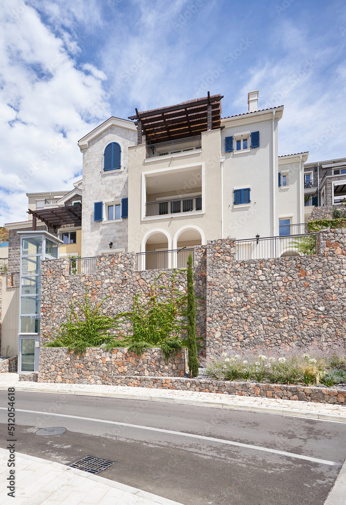 Obraz premium Residential building near the road with a high stone fence