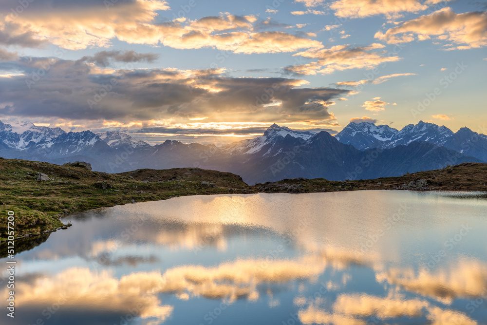 The sun and clouds is reflected in the Arcoglio Lake at sunrise, Valmalenco, Valtellina, Lombardy, Italy The sun and clouds is reflected in the Arcoglio Lake at sunrise, Valmalenco, Valtellina, Lombardy, Italy