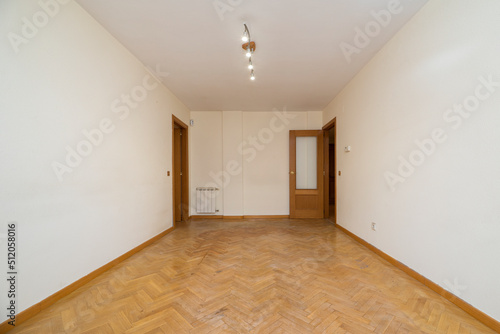 Empty room with white painted walls, herringbone oak parquet flooring, matching woodwork and white radiator © Toyakisfoto.photos