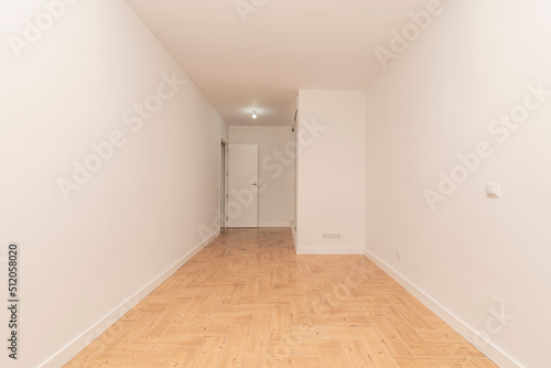 Empty room with white painted walls  cream-colored ceramic tile floor and built-in wardrobe