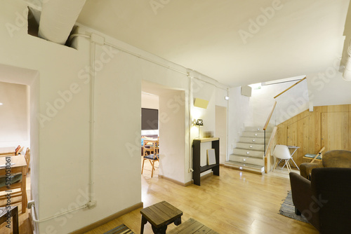 Fototapeta Naklejka Na Ścianę i Meble -  Private dining restaurant with wooden tables, oak parquet flooring, cupboard under the stairs and white painted walls