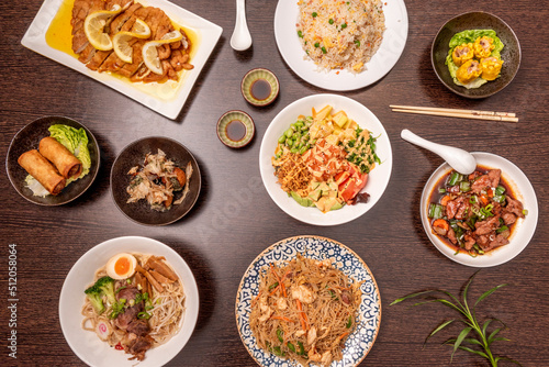 Set of asian food dishes with spring rolls, lemon chicken, three delight rice, spicy beef and pork ramen and noodles