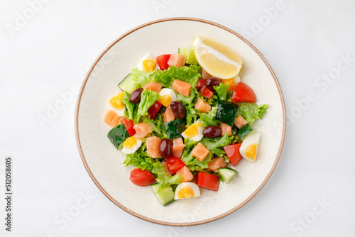 Salmon salad with eggs and vegetables on a white background