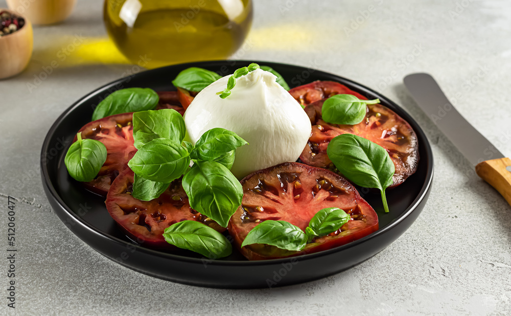 Close up of vegetarian appetizer. Tomatoes and Burrata cheese with fresh basil.