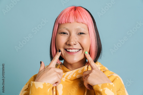 Asian girl with pink hair and piercing pointing fingers at her smile