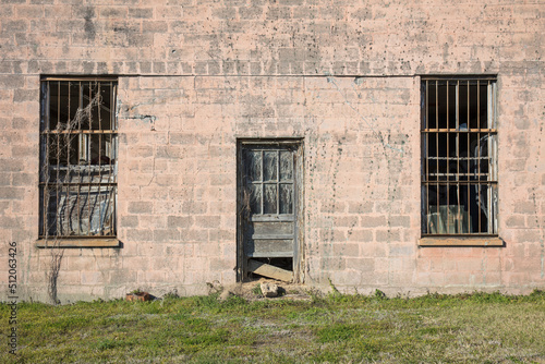 Abandoned jailhouse facade, an empty building with barsont the windows. photo