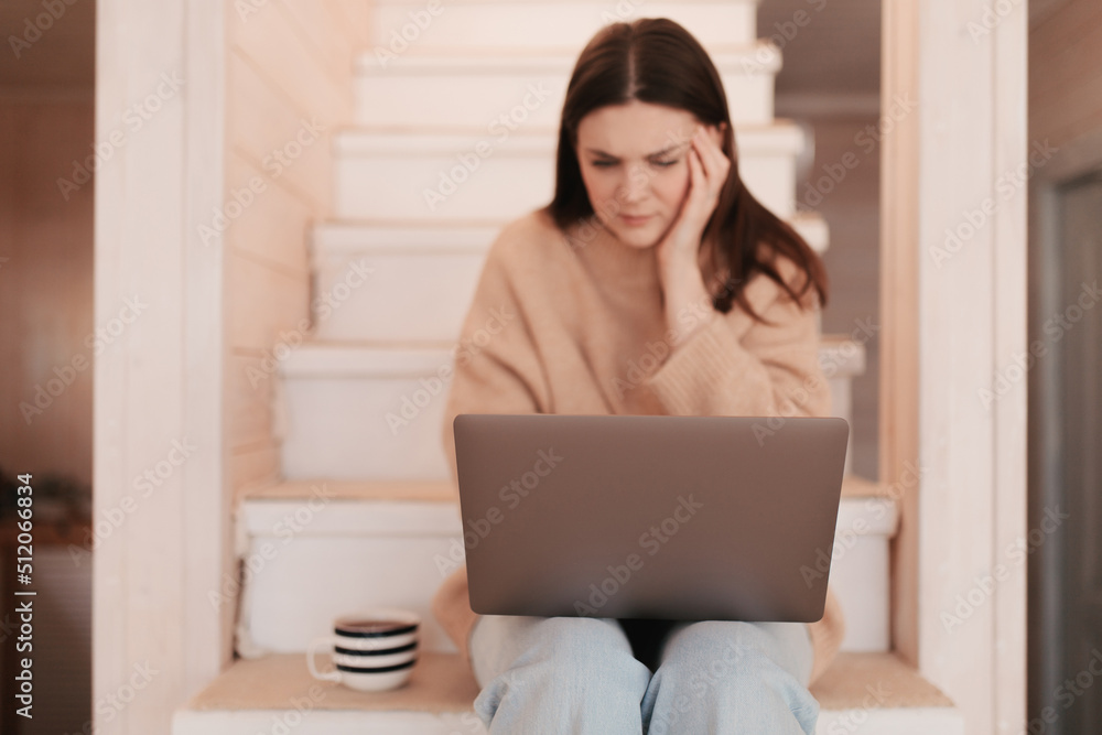 Woman working remotely from her house with a laptop Woman working remotely from her house with a laptop