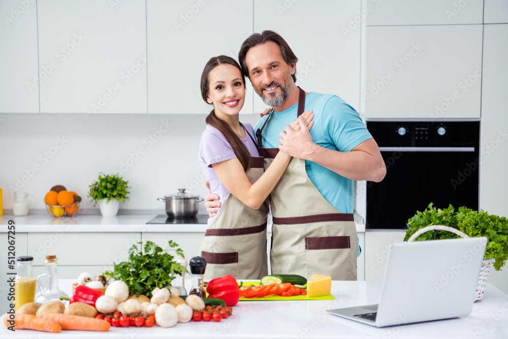 Photo of good mood sweet mature wife husband dressed aprons cuddling cooking lunch indoors home room