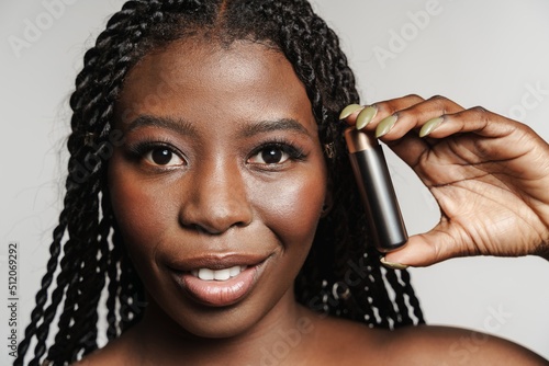 Shirtless black woman smiling while posing with lipstick