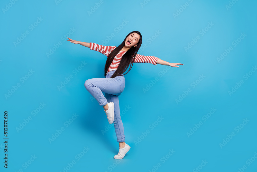 Full length photo of funky excited woman wear striped shirt dancing arms sides isolated blue color background