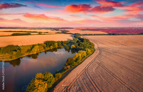 Fantastic summer sunset on outskirts of Ternopil town with small pond. Marvelous evening view from the flying drone of Ukrainian countrysidewith field of wheat. photo