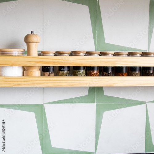 Spices pots alligned in a pinus wooden shelf in a green kitchen. Copyspace and square photograph  photo