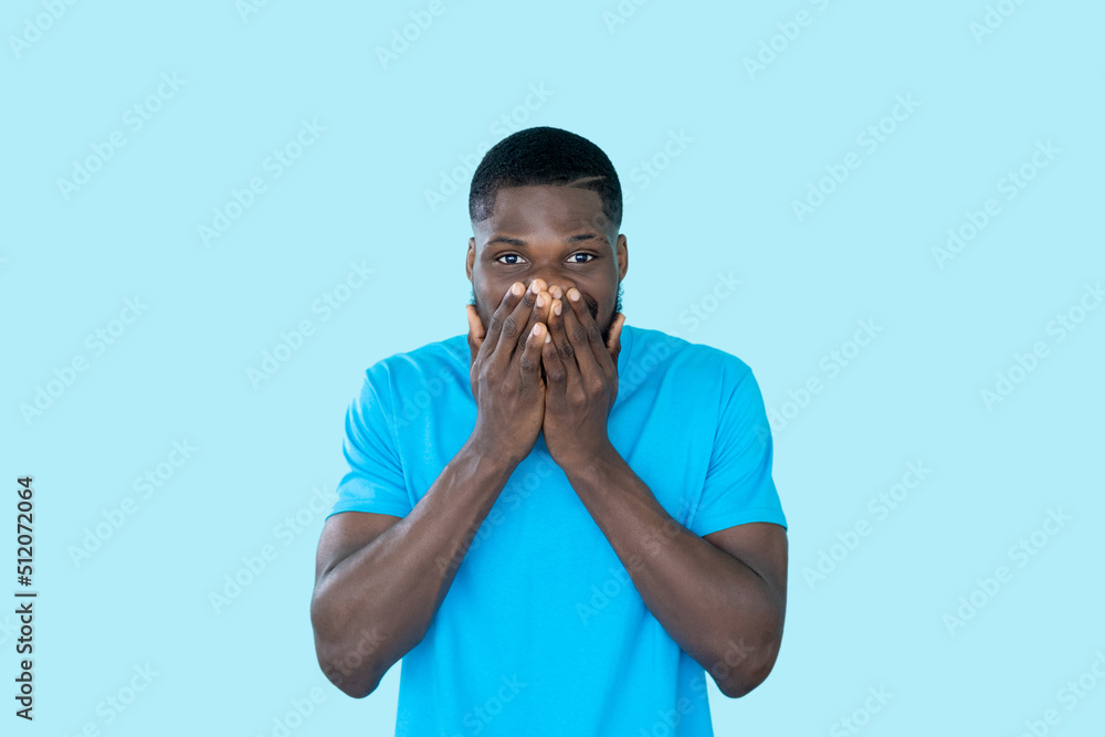 Surprised man. Omg expression. Unexpected news. Amazed shocked speechless emotion guy covering mouth isolated on blue studio background. Surprised man. Omg expression. Unexpected news. Amazed shocked speechless emotion guy covering mouth isolated on blue studio background.