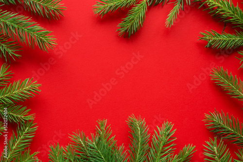Christmas red background from green fir branches  frame  top view